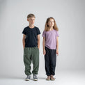 Amo tricou din lână merinos pentru copii; auro-kid-s-fleece-pants-459836-size-banner-large-v-2*: Doi copii în tricou și pantaloni din fleece stau spate în spate, unul dintre ei cu o placă de skateboard