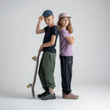 Amo tricou din lână merinos pentru copii; auro-kid-s-fleece-pants-459836-size-banner-large-v-2*: Doi copii în tricou și pantaloni din fleece stau spate în spate, unul dintre ei cu o placă de skateboard